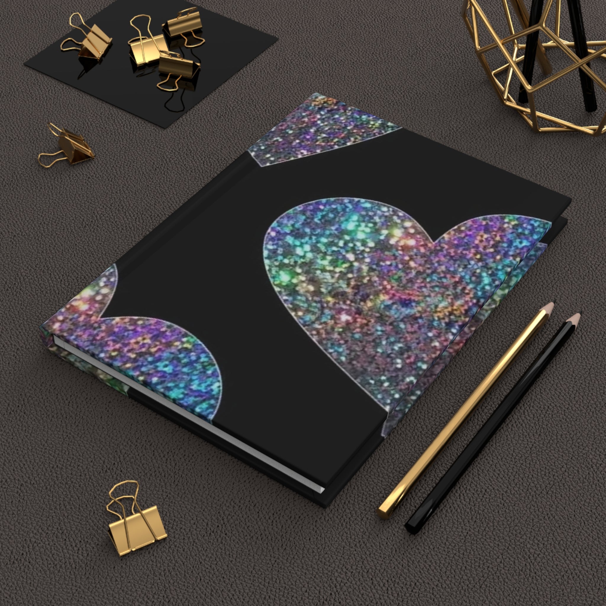 Diario rigido opaco con copertina nera e cuori glitter; penna e graffette in vista